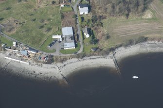 Oblique aerial view of the E searchlight position and fire trench, pillbox, caretakers/guardhouse and RA store, looking NW.