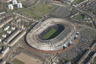 Oblique aerial view of Hampden Park being converted to a Commonwealth games venue, looking to the NE.