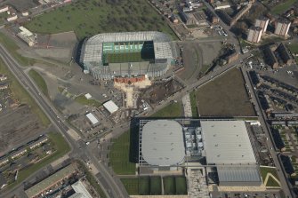 Oblique aerial view of of the Sir Chris Hoy Velodrome and Parkhead football stadium, looking to the NE.