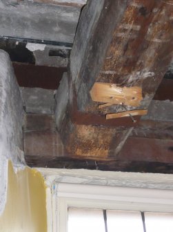 Beam supported by steel strapping hung from lintel over window on north