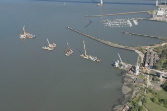 Oblique aerial view of the construction of the Queensferry Crossing on the south bank of the River Forth, looking E.