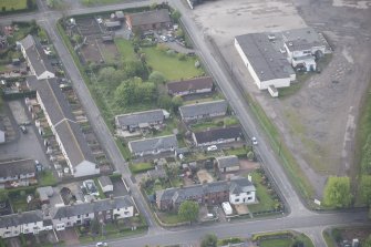 Oblique aerial view of five long rectangular single story timber houses, looking SSW.