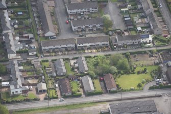 Oblique aerial view of five long rectangular single story timber  houses, looking ESE.