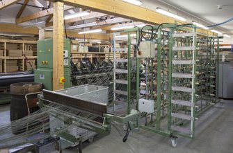 Interior. New weaving shed. View of warping or beaming machine. This takes single yarn strands from many bobbins on the frame and winds under tension onto a beam ready for weaving.