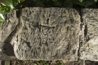 View of cross slab built into South wall of graveyard