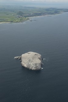 General oblique aerial view of the  Bass Rock with the East Lothian coastline beyond, looking SSW.