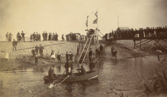 View of water chute in Stonehaven showing crowd of people and rowing boat.