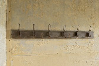 North west range, ground floor, corridor to bathroom, detail of metal coat hooks