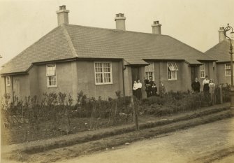 Uncaptioned photograph of people standing in front of a cottage.