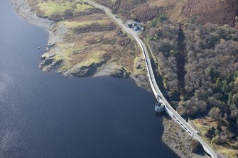 Oblique aerial view of Loch Doon dam and military remains, looking NNE.