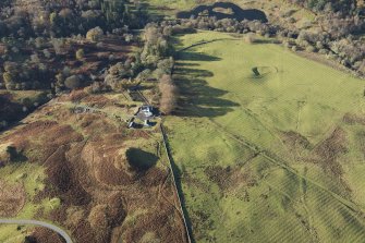 Oblique aerial view of the southern terminal of the Loch Doon Gunnery School railway,  cutting across the field and ending at a small loading platform by the Gaw Glen Burn, looking W.