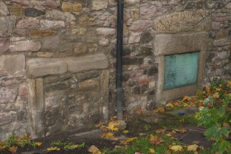 Detail of blocked openings (possibly reused stone) and commemorative plaque in south elevation of Harry Younger Hall, Lochend Close, Canongate, Edinburgh.