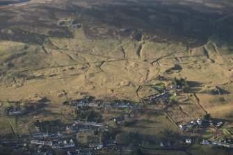 Oblique aerial view of Leadhills village, the mining remains and the field systems, looking W.