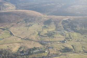 Oblique aerial view of the mining and cultivation remains with the souther part of Leadhills village in the foreground, looking ESE.