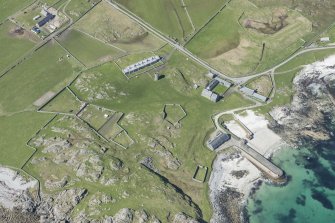 Oblique aerial view of Hynish Lighthouse shore establishment and harbour on Tiree, looking WNW.