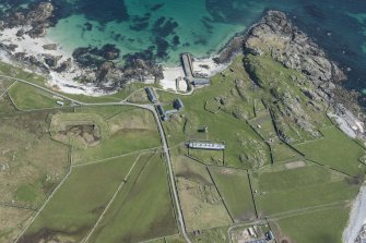 Oblique aerial view of Hynish Lighthouse shore establishment, reservoir  and harbour on Tiree, looking ENE.