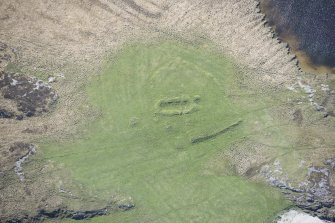 Oblique aerial view of a building lying within an area of rig and furrow at Loch Dubh a Gharaidh Fail on the Isle of Tiree, looking S.
