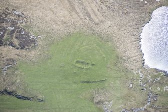 Oblique aerial view of a building lying within an area of rig and furrow at Loch Dubh a Gharaidh Fail on the Isle of Tiree, looking SSE.