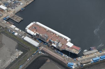 Oblique aerial view of the Main Basin, Rosyth Naval Dockyard showing the construction of an aircraft carrier, looking ENE.