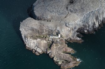 Oblique aerial view of part of the Bass Rock centred on the lighthouse, looking NNW.