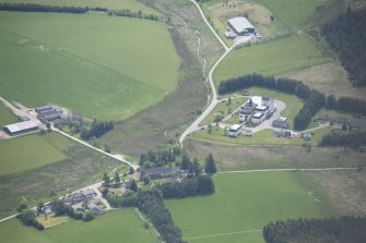 Oblique aerial view of the Braes of Glenlivet Distillery and Chapeltown Roman Catholic Church of Our Lady of Perpetual Succour, chapel house and burial ground, looking SE.