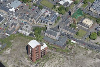 Oblique aerial view of Dumbarton Distillary and Riverside Parish Church, looking NW.