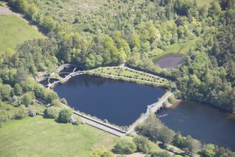 Oblique aerial view of Mugdock Resevoir measuring pond, footbridge and sluice , looking NNE.