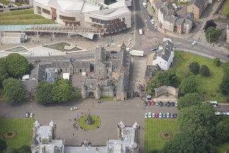 Oblique aerial view of Holyrood Palce gatehouse, Abbey Court, Holyrood Palace Yard fountain, Memorial to King Edward VII, Thomson's Court and 11, 13, 15 Canongate, looking WSW.