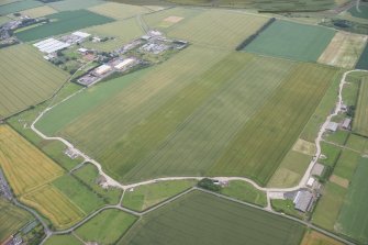 General oblique aerial view of Drem Airfield and the cropmarks of the palisaded enclosure and pit defined boundary, looking SSE.