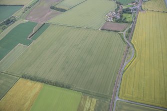 Oblique aerial view of the cropmarks of the enclosure and the  possible sunken-floored buildings with Drem village beyond, looking ENE.