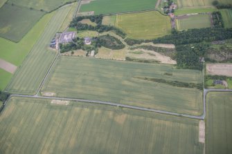 Oblique aerial view of the cropmarks of the sunken floored buildings, looking N.