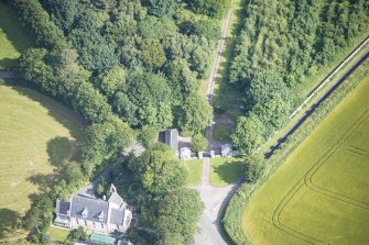 Oblique aerial view of Cairness House South Lodge and St Columba's Episcopal Church, looking NNW.