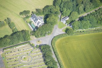 Oblique aerial view of Cairness House South Lodge and St Columba's Episcopal Church, looking NW.
