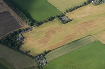 Oblique aerial view of the cropmarks of the sunken floored building, the enclosure, pits and rig, looking NNE.