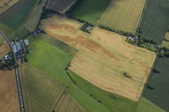 Oblique aerial view of the cropmarks of the sunken floored building, the enclosure, pits and rig, looking NNW.