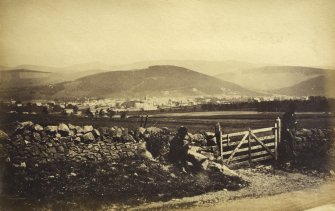 Distant view of Peebles showing man by stone wall