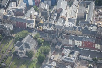 Oblique aerial view of the Canongate, Canongate Tolbooth, Canogate Parish Church and Huntly House, looking SSE.