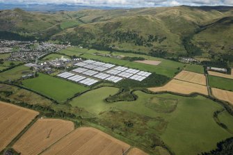 General oblique aerial view centred on Glenochil distillery and adjoining warehouses, looking NW.
