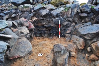 Charcoal-rich and fire-cracked stone layer on west side of rubble wall - visible in north facing Trench 1 section, Comar Wood Dun, Cannich, Strathglass