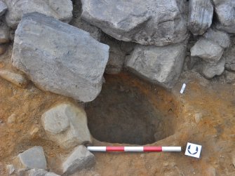 Post-excavation image of posthole 122 with wall 102 over the south edge, Comar Wood Dun, Cannich, Strathglass