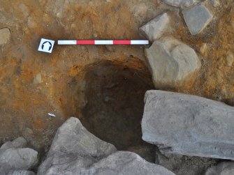 Post-excavation image of posthole 122 with wall 102 over the south edge, Comar Wood Dun, Cannich, Strathglass