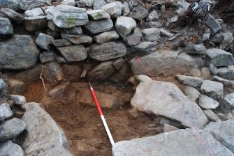 Mid-excavation image of charcoal-rich material outside dun outer wall face, Comar Wood Dun, Cannich, Strathglass