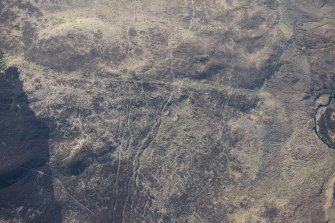 Oblique aerial view of the hut circles and field system at Drumturn Burn in Glen Shee, looking S.