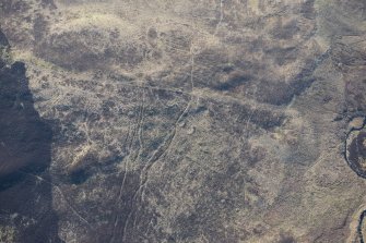 Oblique aerial view of the hut circles and field system at Drumturn Burn in Glen Shee, looking S.