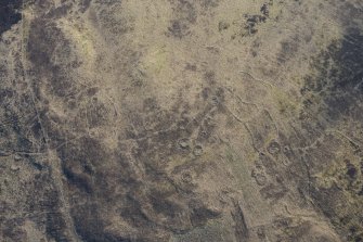 Oblique aerial view of the hut circles and field system at Drumturn Burn in Glen Shee, looking E.