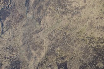 Oblique aerial view of the hut circles and field system at Drumturn Burn in Glen Shee, looking N.