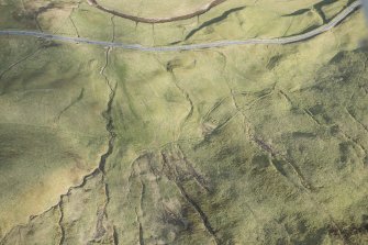 Oblique aerial view of a farmstead, mill and other buildings in Gleann Beag, looking SE.