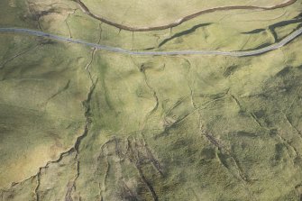 Oblique aerial view of a farmstead, mill and other buildings in Gleann Beag, looking ESE.