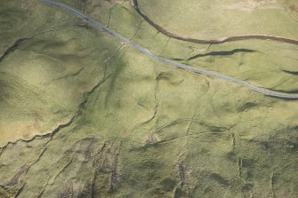 Oblique aerial view of a farmstead, mill and other buildings in Gleann Beag, looking ESE.