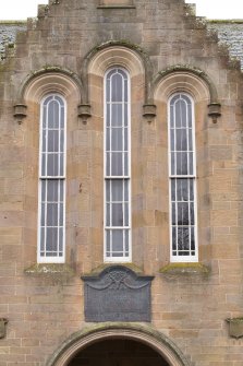 Detail of round-headed lancet windows and war memorial.